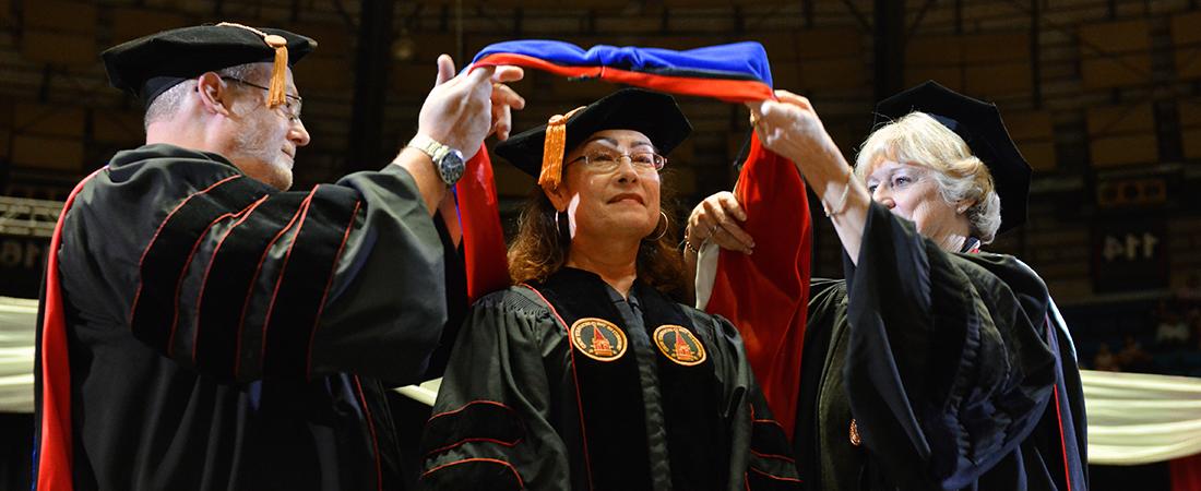 Dean and director hooding student at graduation